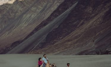A couple enjoying a camel ride in the stunning landscapes of Nubra Valley, Ladakh, India.