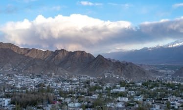 Breathtaking view of Leh town surrounded by towering mountains and clear blue skies.