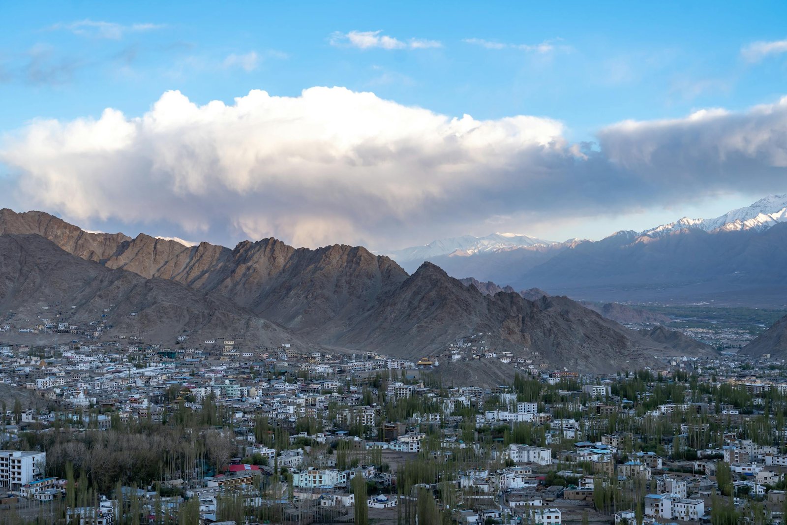 Breathtaking view of Leh town surrounded by towering mountains and clear blue skies.