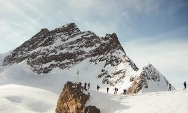 Group of hikers trekking across a snowy mountain range under a clear sky, capturing the essence of adventure.