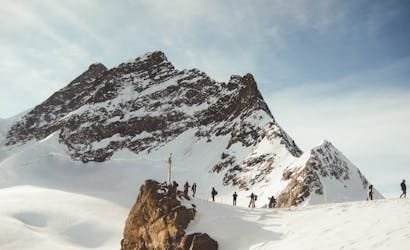 Group of hikers trekking across a snowy mountain range under a clear sky, capturing the essence of adventure.