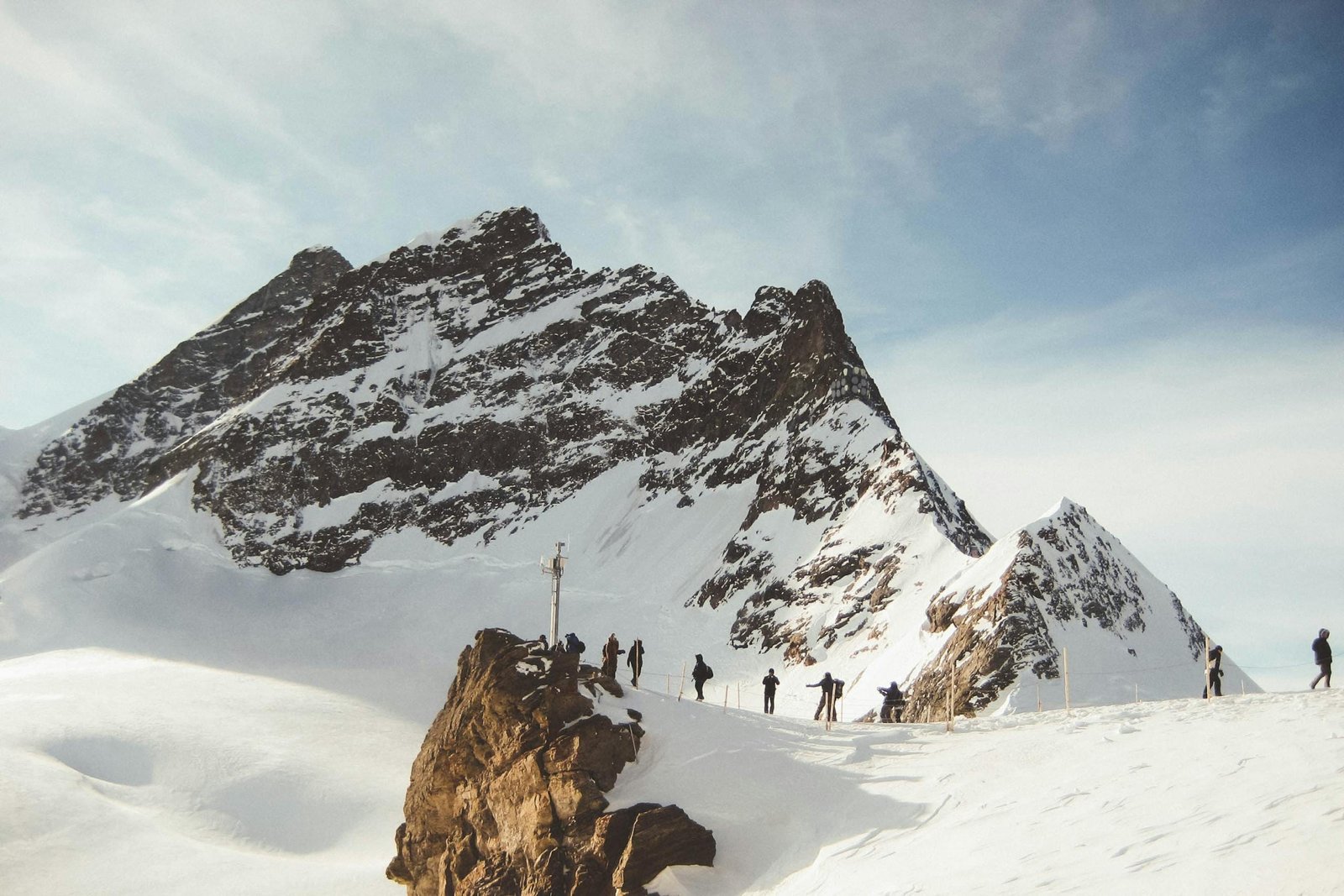 Group of hikers trekking across a snowy mountain range under a clear sky, capturing the essence of adventure.