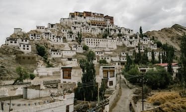 Scenic view of Thiksey Monastery nestled in the mountains of Ladakh, India with overcast skies.