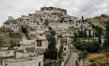 Scenic view of Thiksey Monastery nestled in the mountains of Ladakh, India with overcast skies.