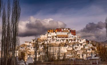 Stunning view of Thiksey Monastery under dramatic clouds in Leh, India.